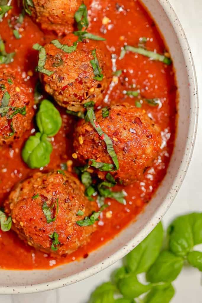 photo of three red meatballs and fresh herbs chopped and garnished on top