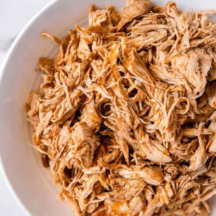 overhead photo of shredded chicken in a white bowl