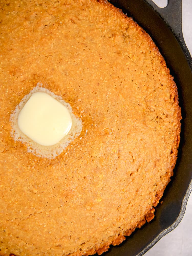 cornbread in a cast iron skillet with melting butter in the center