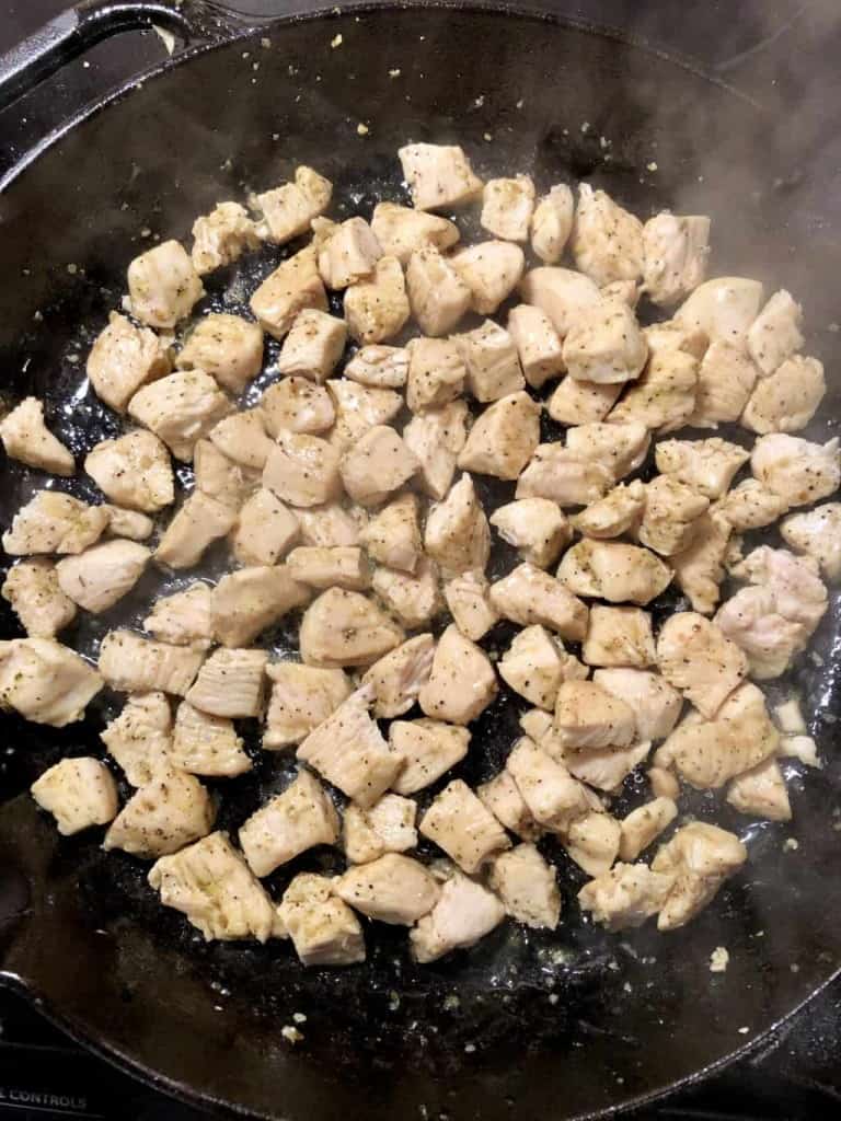 cubed chicken cooking in a cast iron skillet