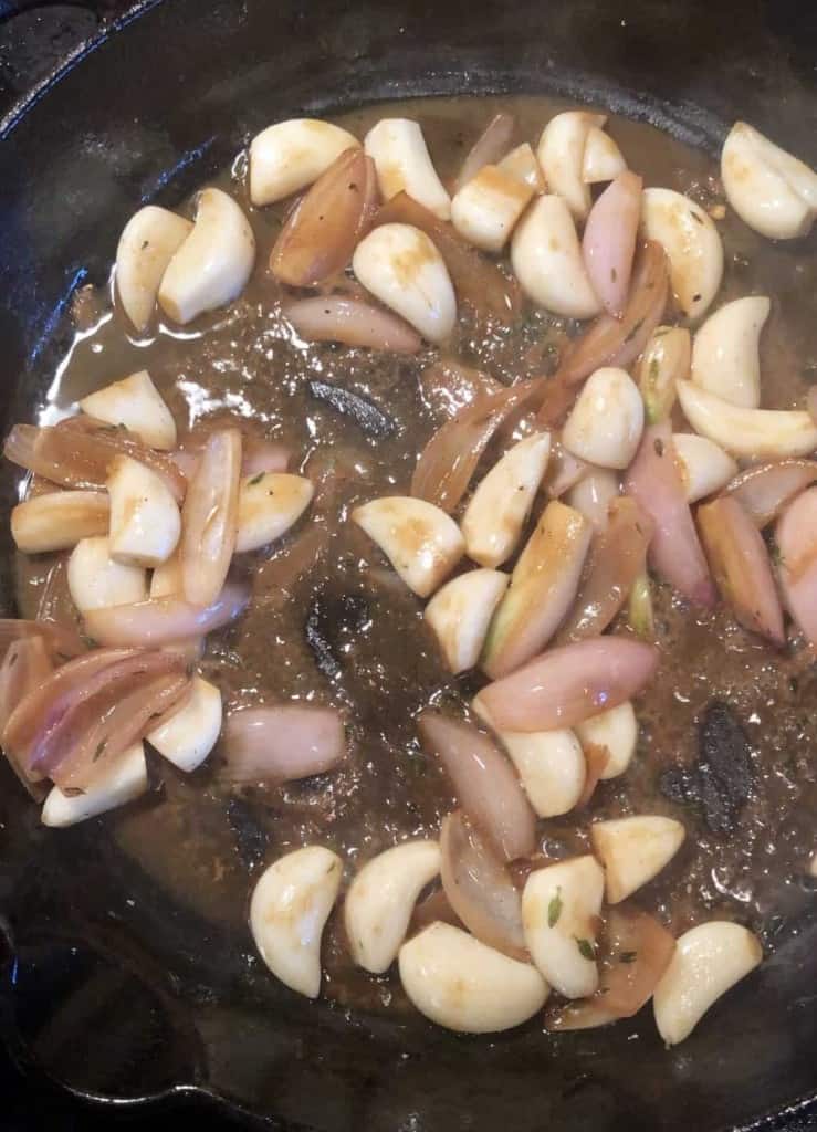 searing whole cloves of garlic and shallots deglazing in cast iron skillet