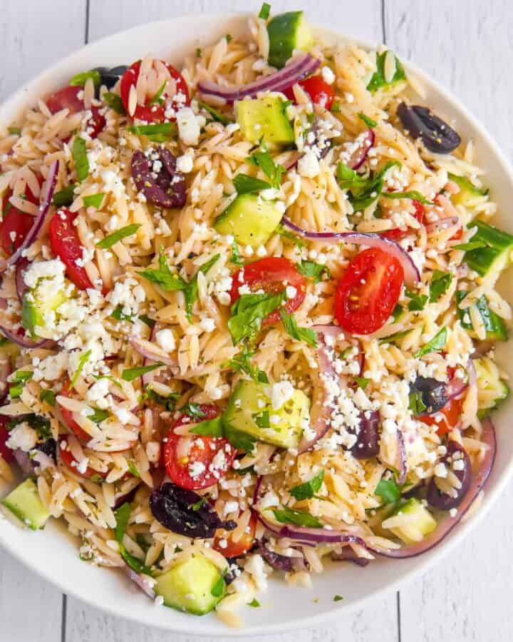 overhead photo of white bowl filled with orzo and greek ingredients