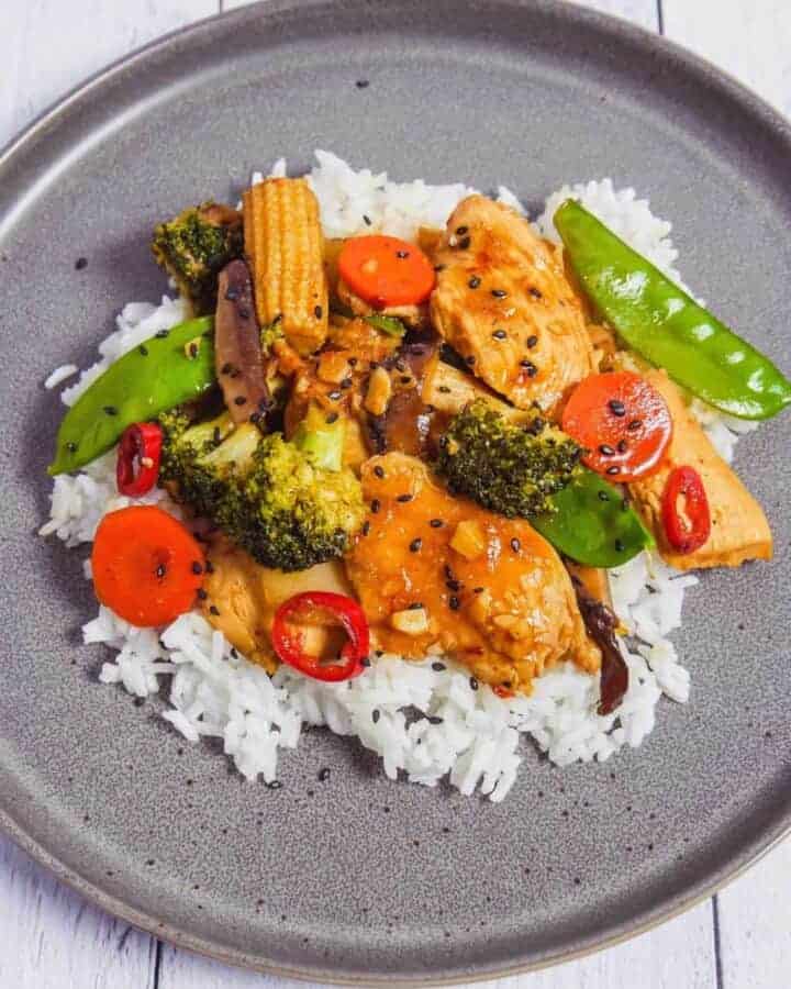 Chicken stir fry with vegetables on a grey plate