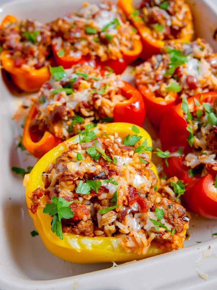 close up photo of stuffed yellow pepper in a baking dish filled with sausage and rice