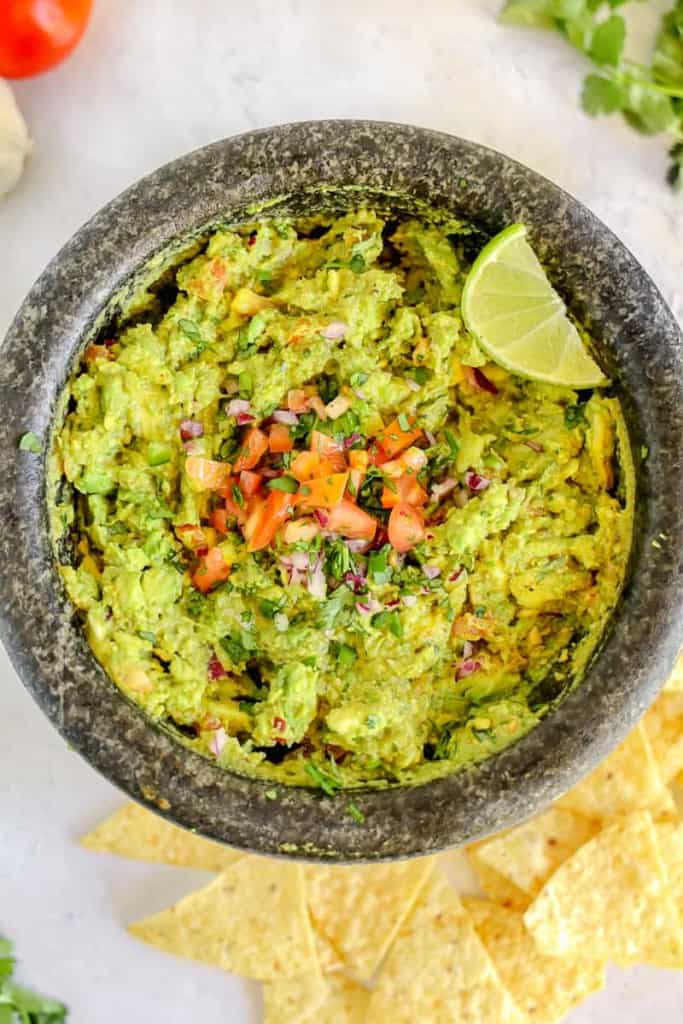 guacamole in a molcajete surrounded by chips
