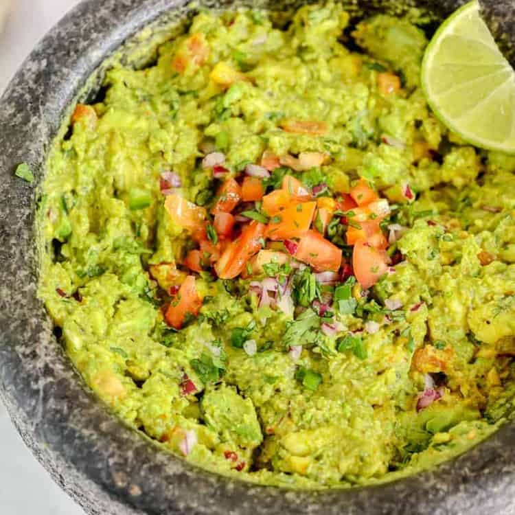 guacamole in a molcajete surrounded by chips