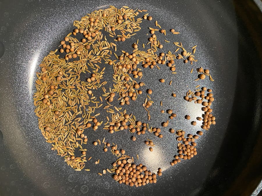 coriander seeds and cumin seeds toasting in a pan