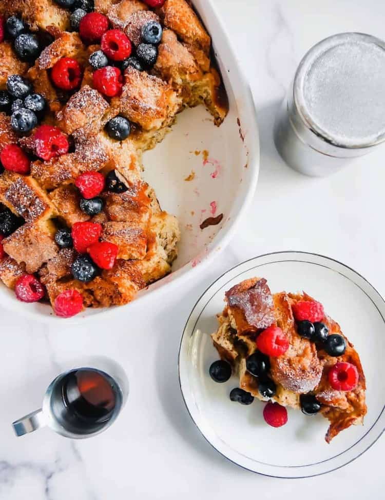 french toast casserole with berries and maple syrup and powdered sugar