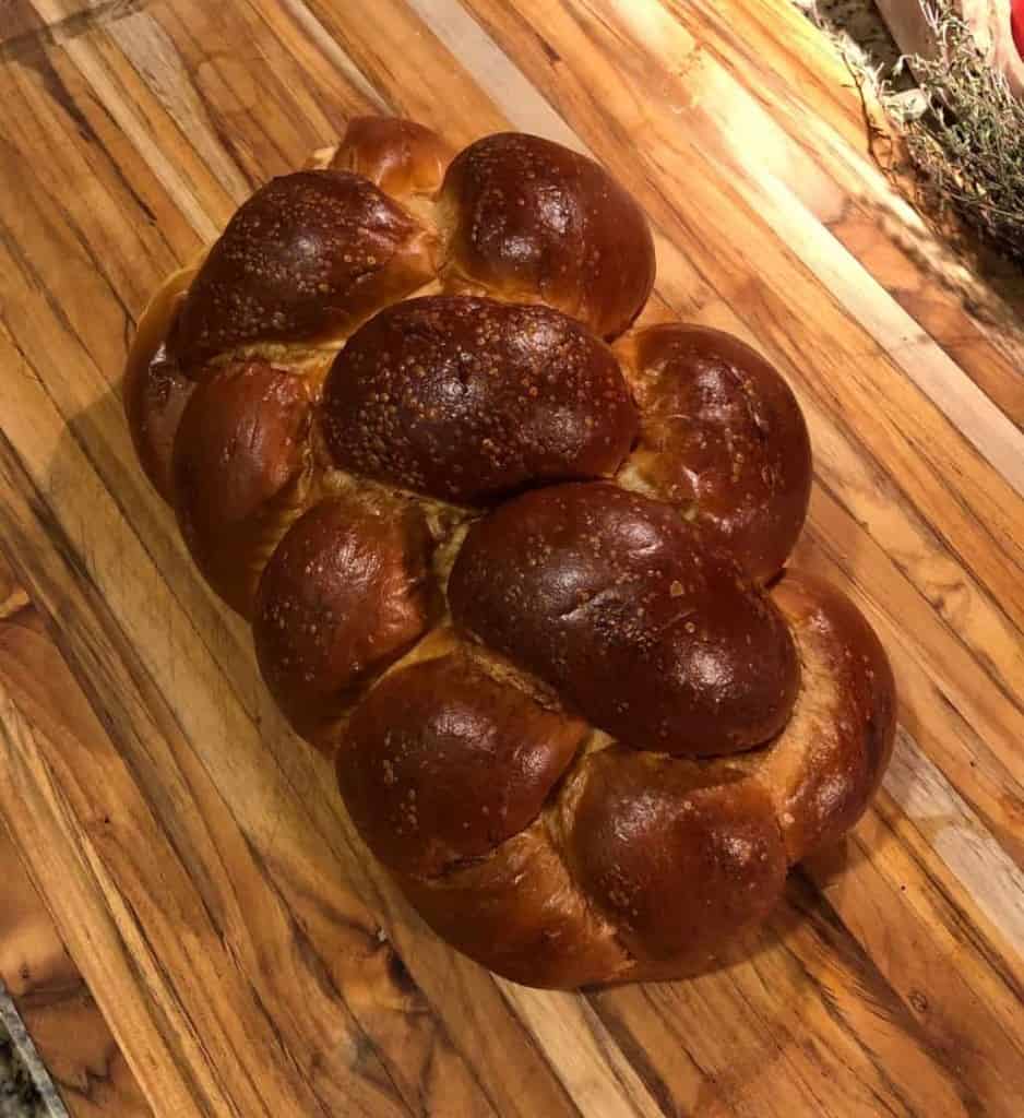 uncut challah bread on a wooden cutting board