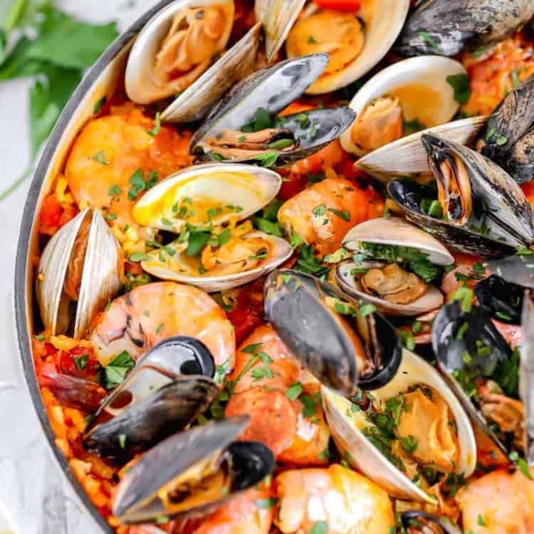 seafood paella in a cast iron with shrimp, clams, mussels on top