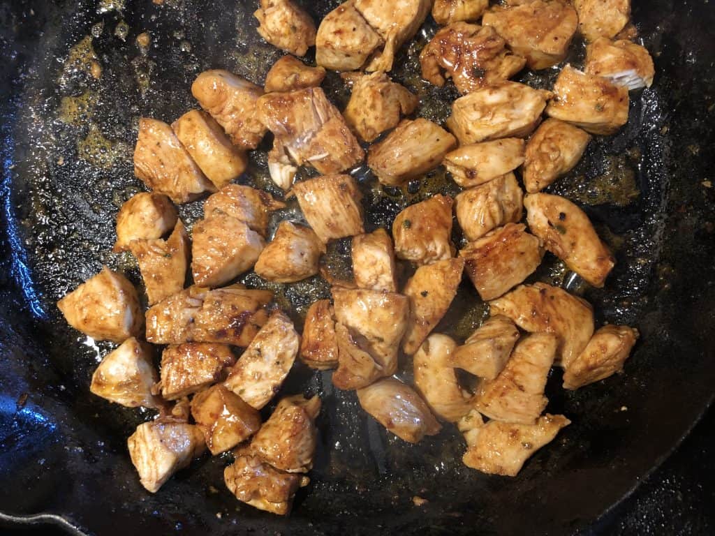 chicken cooking in a cast iron skillet 