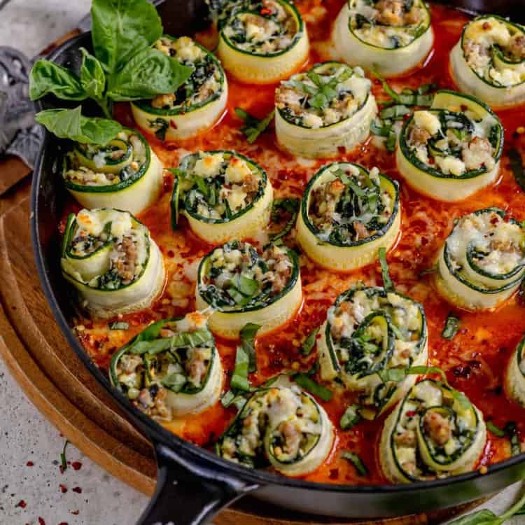 stuffed zucchini rolls in a cast iron skillet with red sauce
