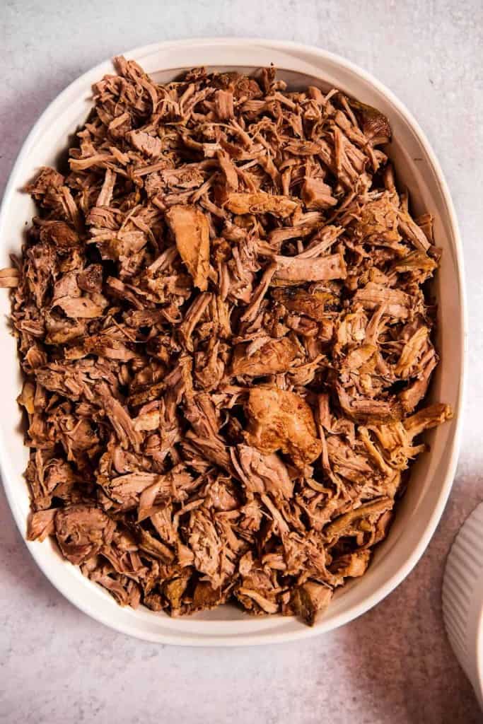 overhead shot of a white baking dish with shredded pulled pork inside 
