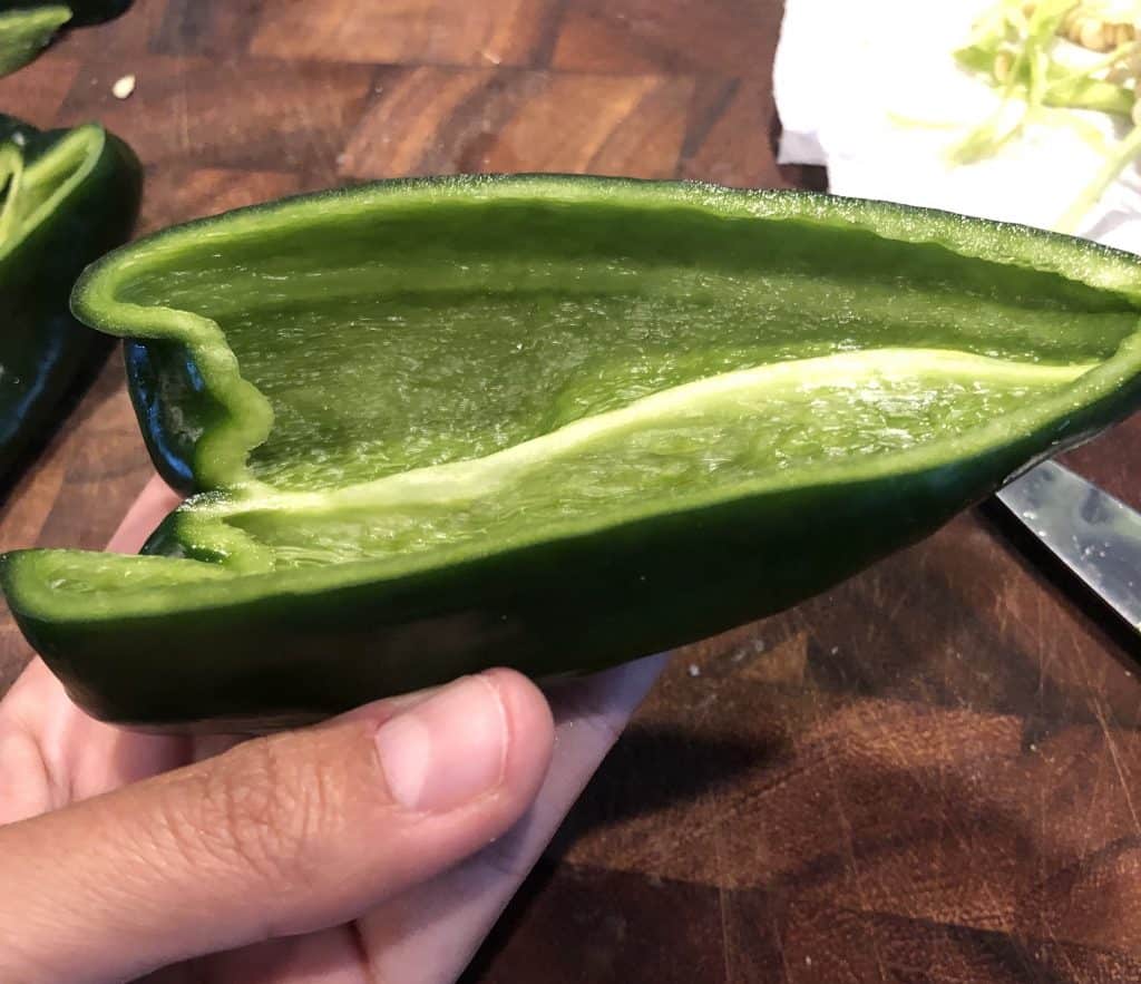 cut in half poblano pepper being held in hand