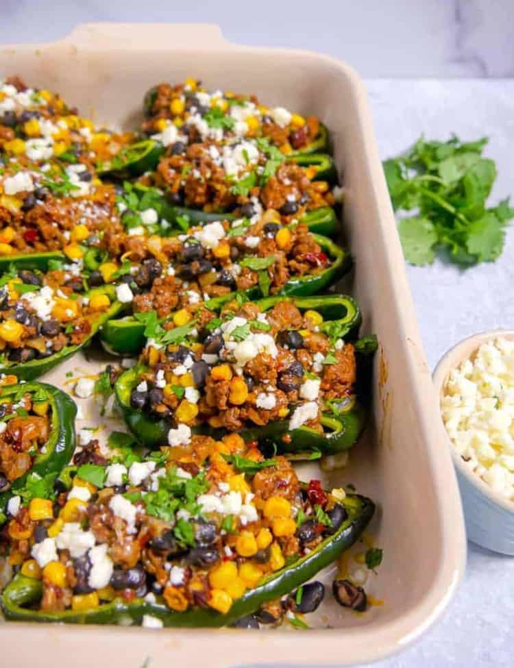 baking dish with poblano peppers stuffed with beef, black beans, corn