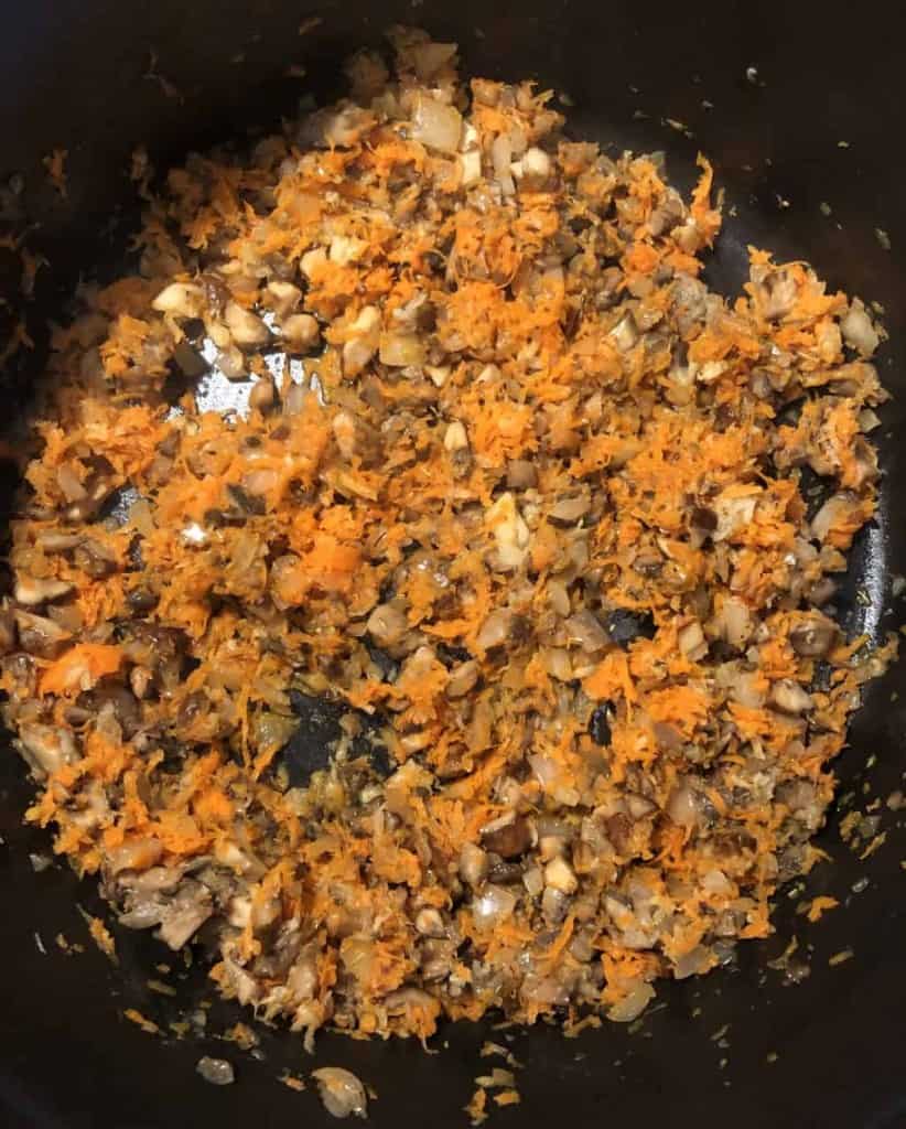 overhead shot of carrot, mushrooms, and onion in a dutch oven