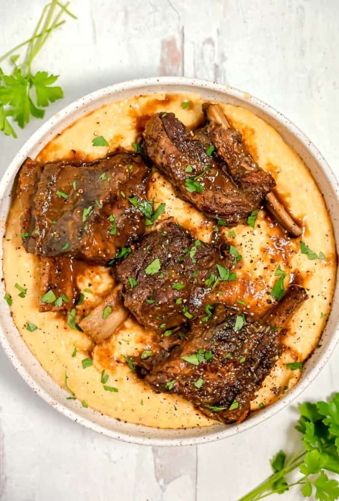 overhead bowl of baked polenta with 4 beef short ribs on top
