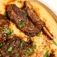 bowl of polenta with short ribs on top and gravy