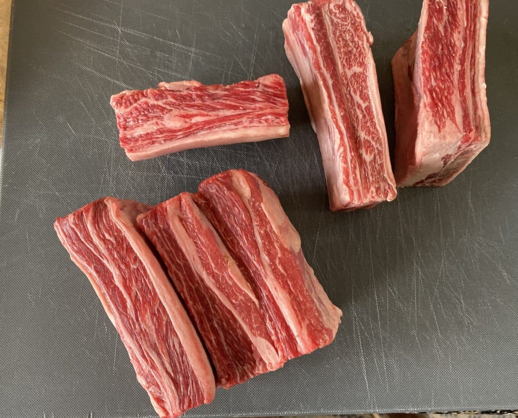 raw beef short ribs laying on a cutting board