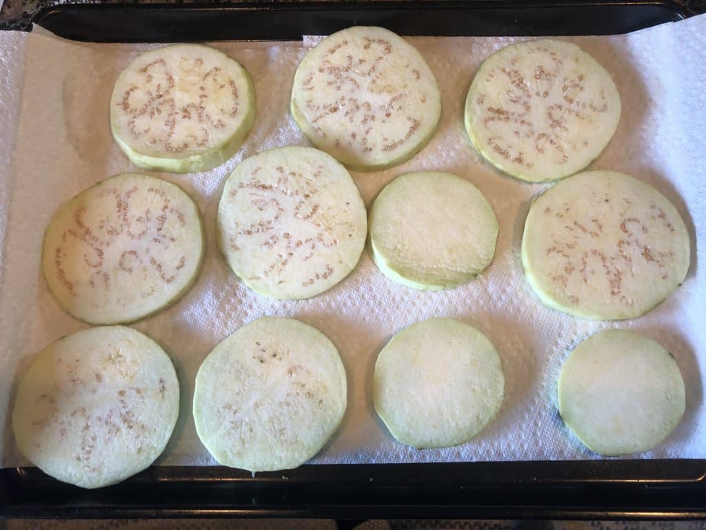 sliced eggplants on a baking sheet lined with paper towels
