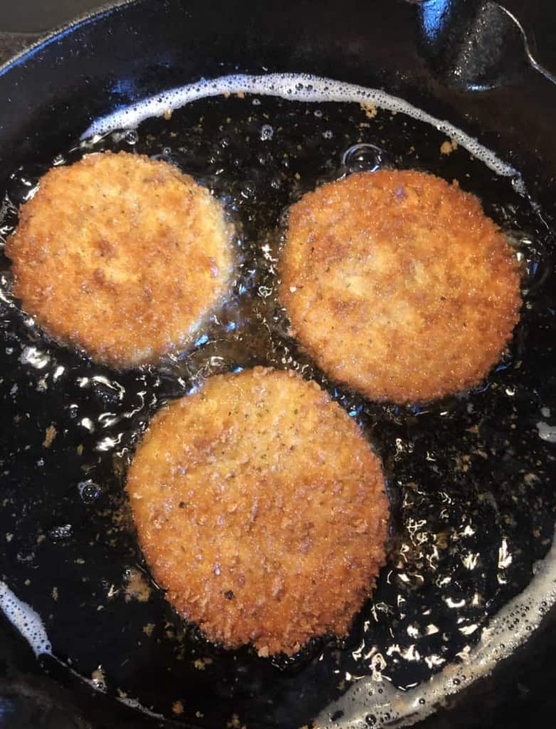 3 slices of eggplant shallow frying in a cast iron skillet