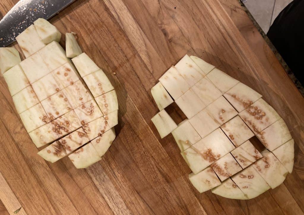 two eggplant steaks on a wooden cutting board diced
