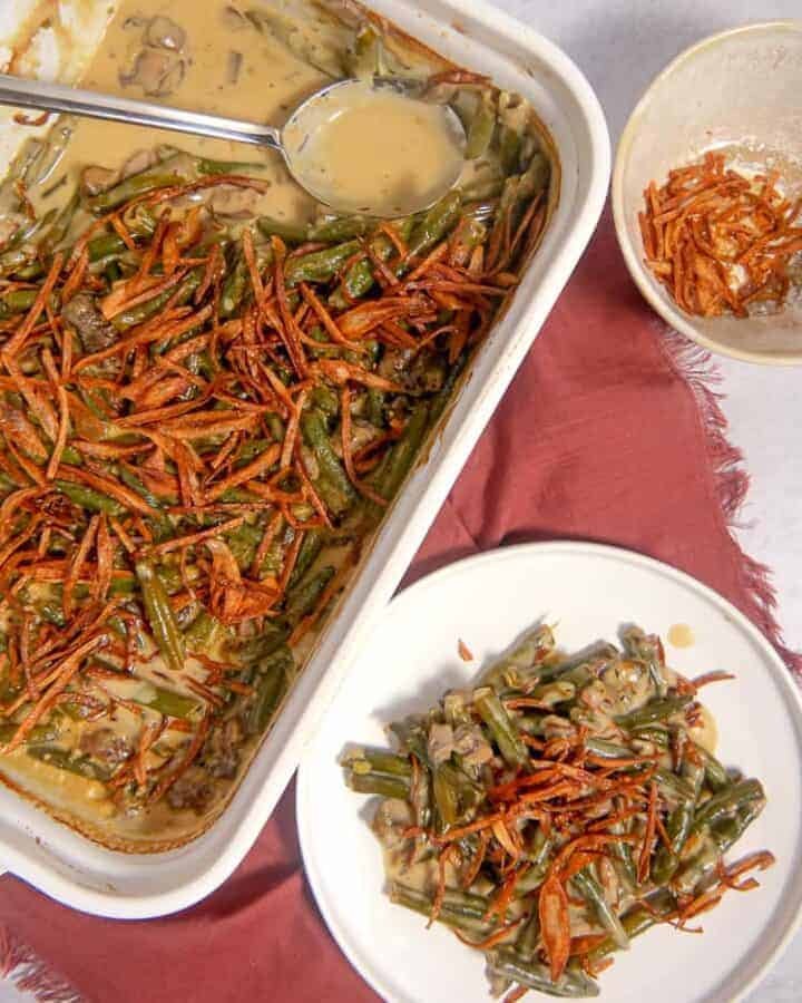 overhead photo of a baking dish with green bean casserole, a plate of green bean casserole, and a bowl of fried shallot