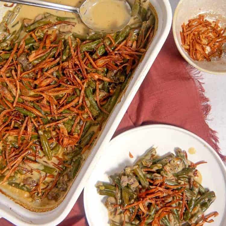 overhead photo of a baking dish with green bean casserole, a plate of green bean casserole, and a bowl of fried shallot