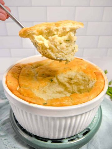 soufflé dish with mashed potato soufflé being lifted out with a spoon
