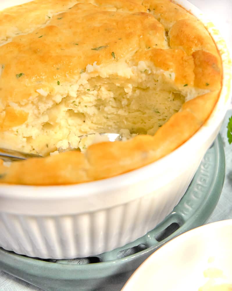 potato soufflé with a big spoon of it removed showing the inside of the soufflé