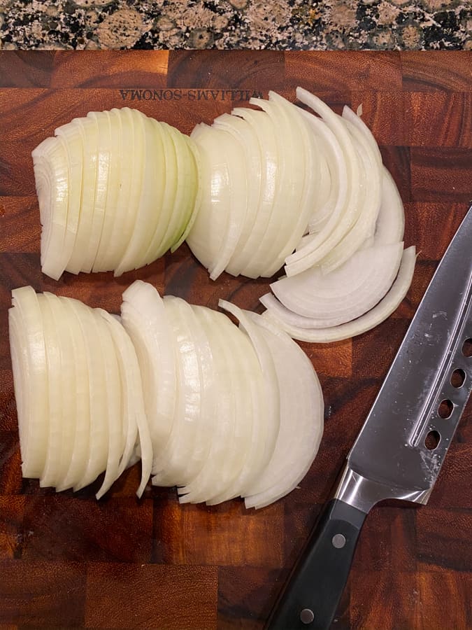 sliced onions on a cutting board with a knife