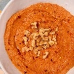 overhead photo of red pepper dip in a white bowl