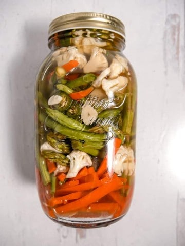 Overhead photo of vegetables in a large jar with pickling liquid