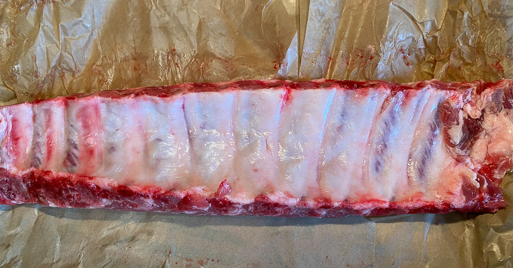photo of underneath of raw rack of baby back ribs 