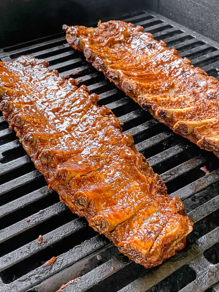 dry rub ribs on the grill with bbq sauce on them