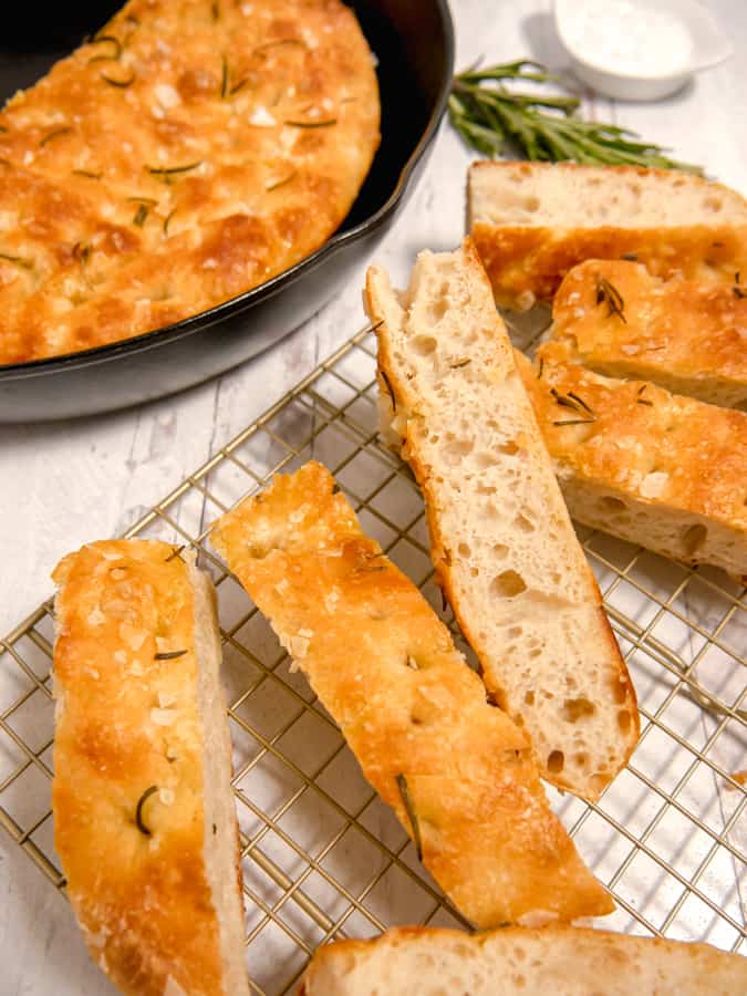 close up of sliced focaccia bread with cast iron in background