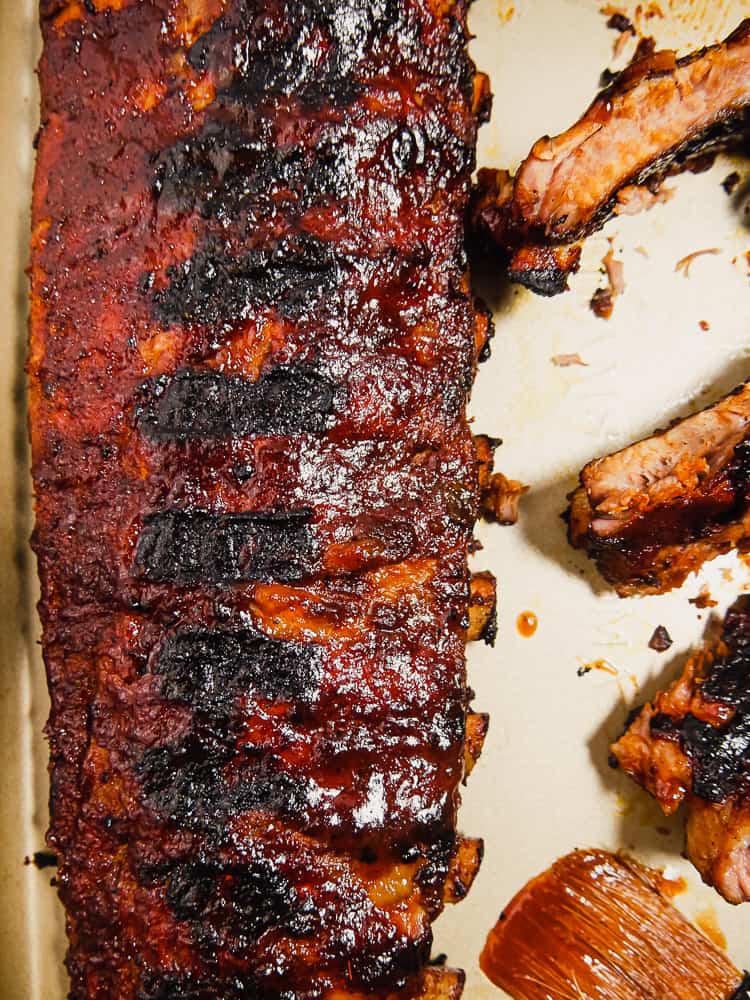close up of BBQ rack of ribs on platter with BBQ brush to the side