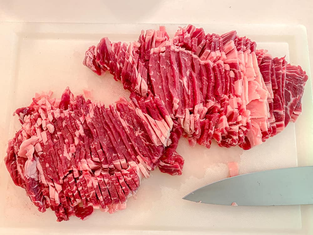 thinly sliced rib eye steak on a cutting board