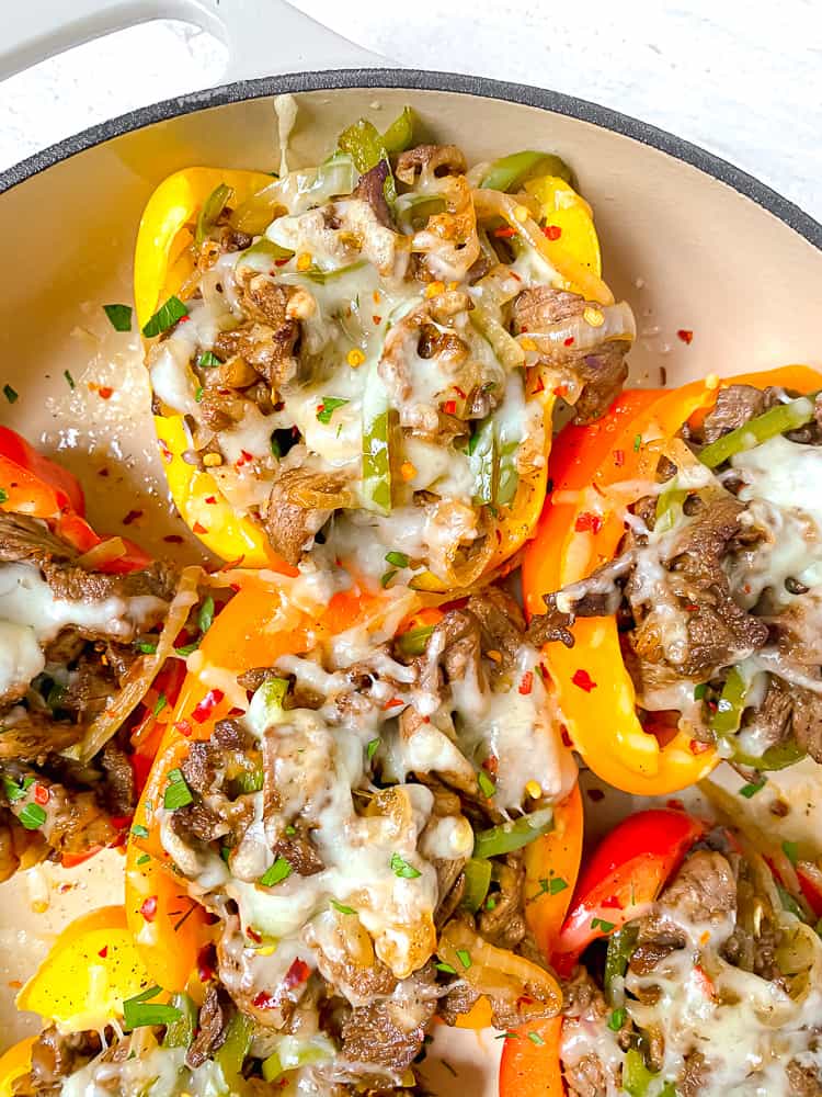 close up of colored bell peppers stuffed with steak, cheese, onions, and peppers on a white backdrop