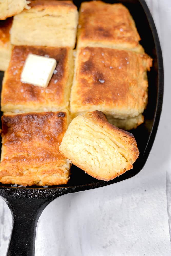 cast iron skillet with square biscuits and slice of butter