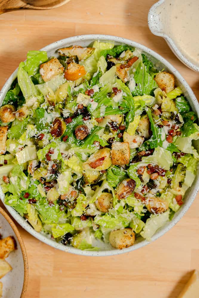 overhead bowl of caesar salad with brussels sprouts and croutons
