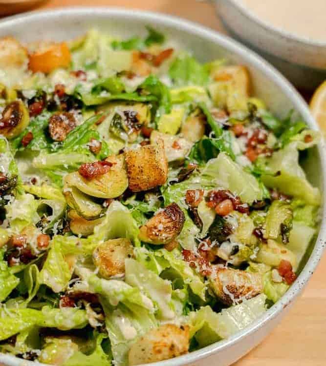 bowl with brussels sprouts, lettuce, pancetta, and croutons, with caesar dressing
