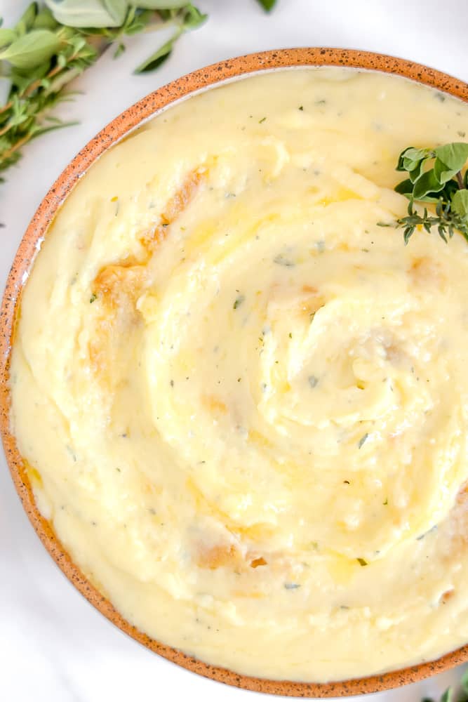 close up of mashed potatoes with herbs and roasted garlic in bowl