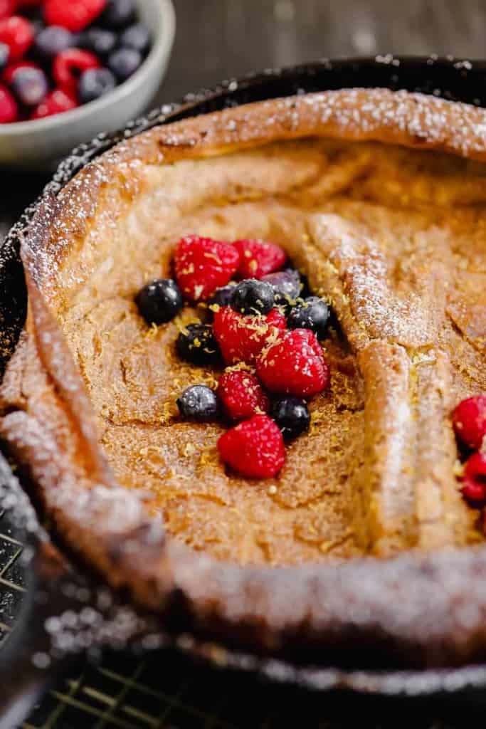close up of dutch baby pancake with berries and lemon zest