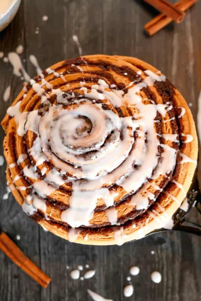 giant cinnamon roll in a skillet with drizzled frosting on top
