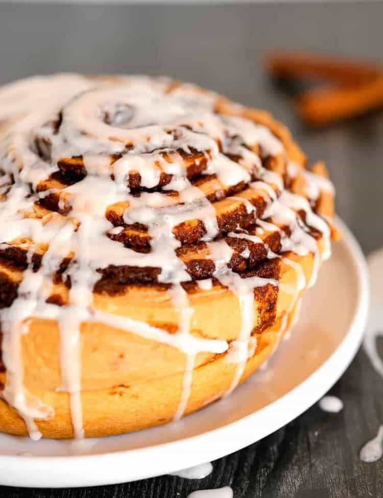 close up of giant cinnamon roll on a plate with frosting