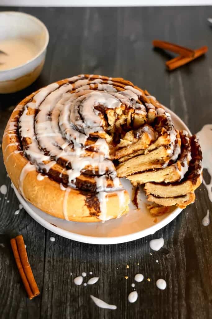 giant cinnamon bun on a plate with section cut out showing layers