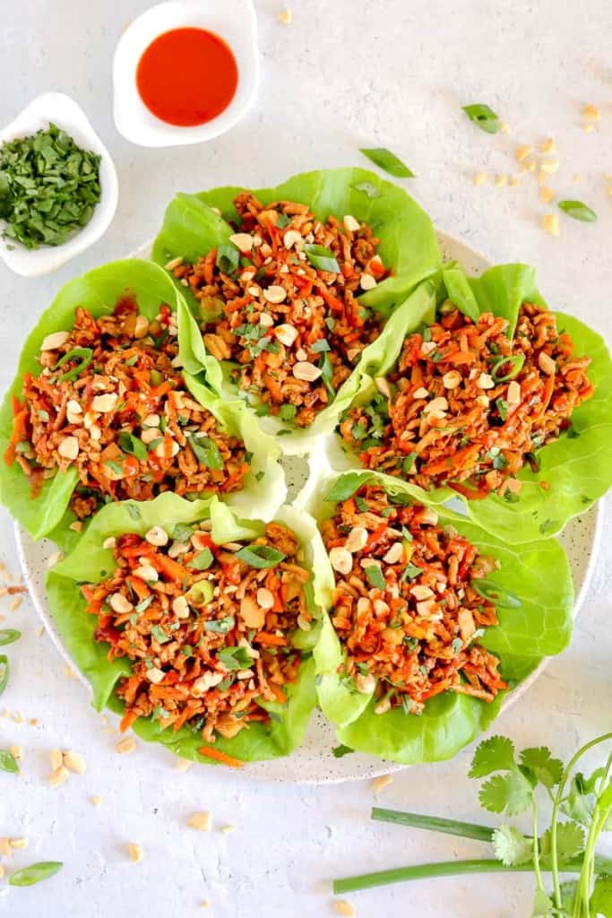 plate with lettuce cups fanned around stuffed with chicken carrots and more