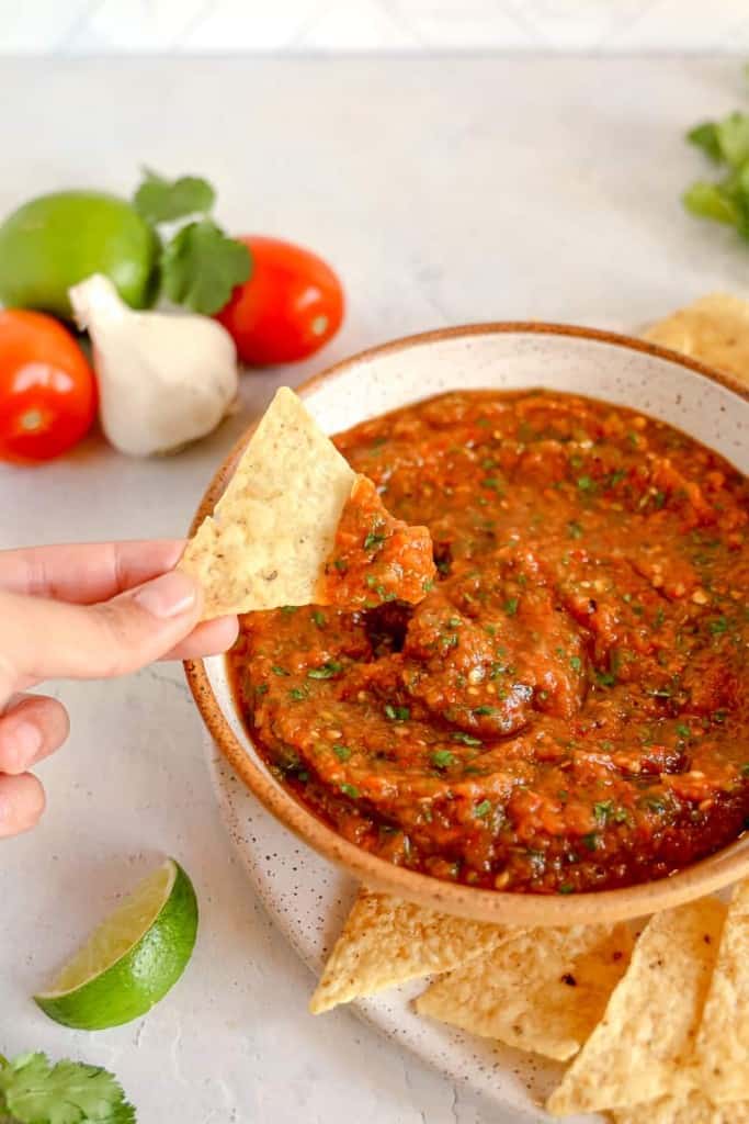 bowl of salsa with a tortilla chip being dipped inside