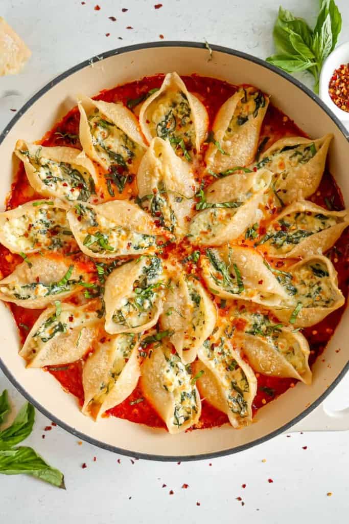 overhead of stuffed pasta shells in red sauce with fresh basil